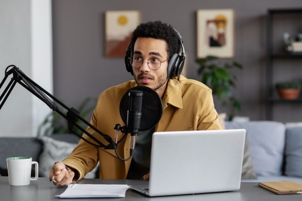 Medium shot of a young man recording a podcast in a studio