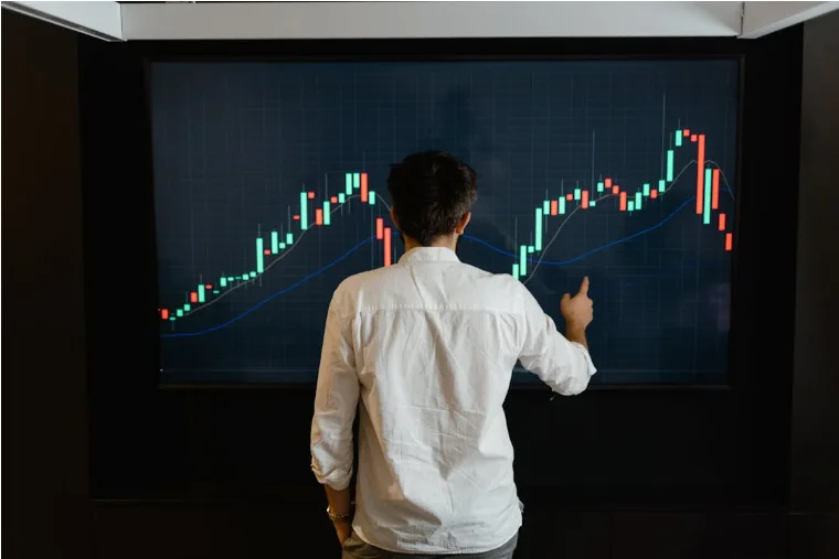 A man looking at chart on a big screen on the wall