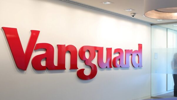 Large red Vanguard logo mounted on a white office wall inside a modern corporate workspace.