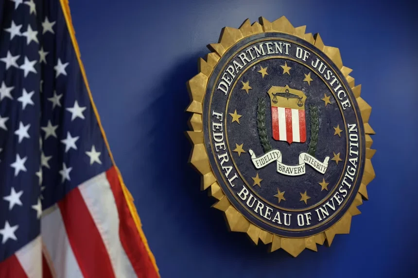 The FBI seal displayed on a blue wall beside a partially visible American flag.