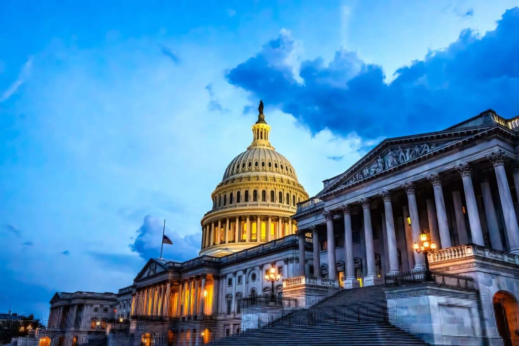 U.S. Capitol building illuminated at dusk under a dramatic blue sky.