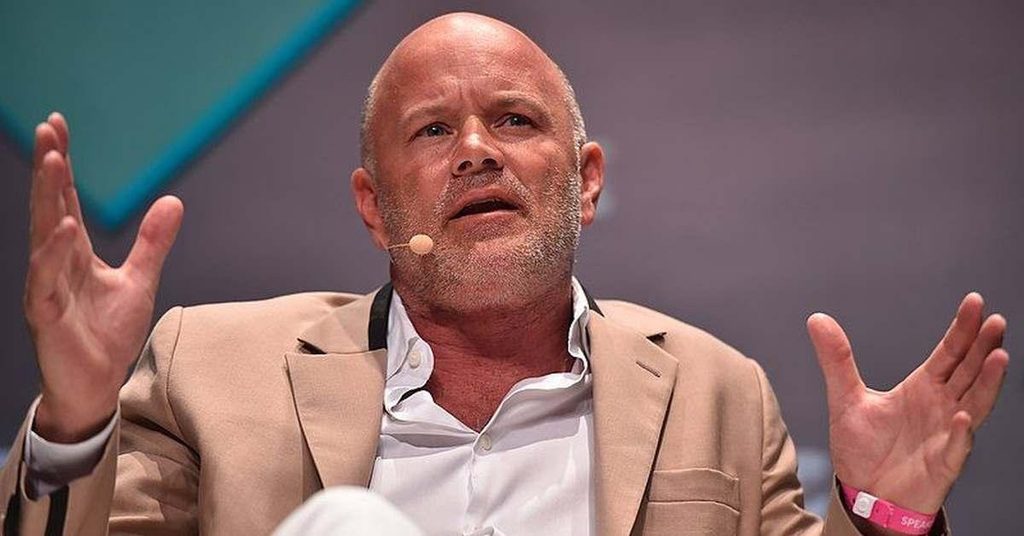 Image of Mike Novogratz wearing a tan suit and a white shirt with a pink wristband