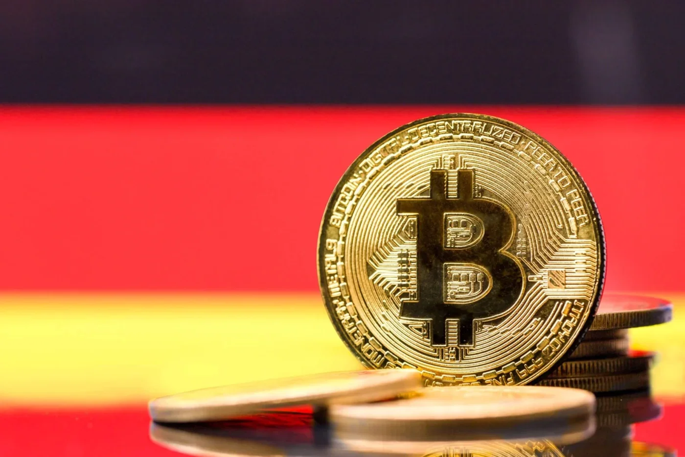 Gold Bitcoin coin with stacked coins against the German flag, representing cryptocurrency and digital asset activity in Germany.